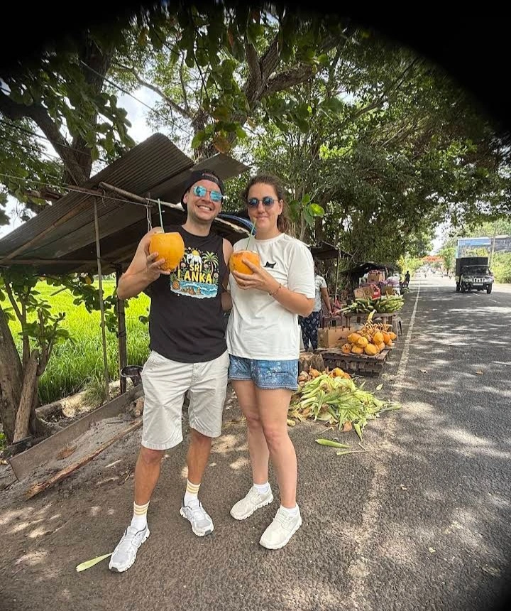title="A couple of guests enjoying refreshing king coconuts during their Sri Lanka holiday."