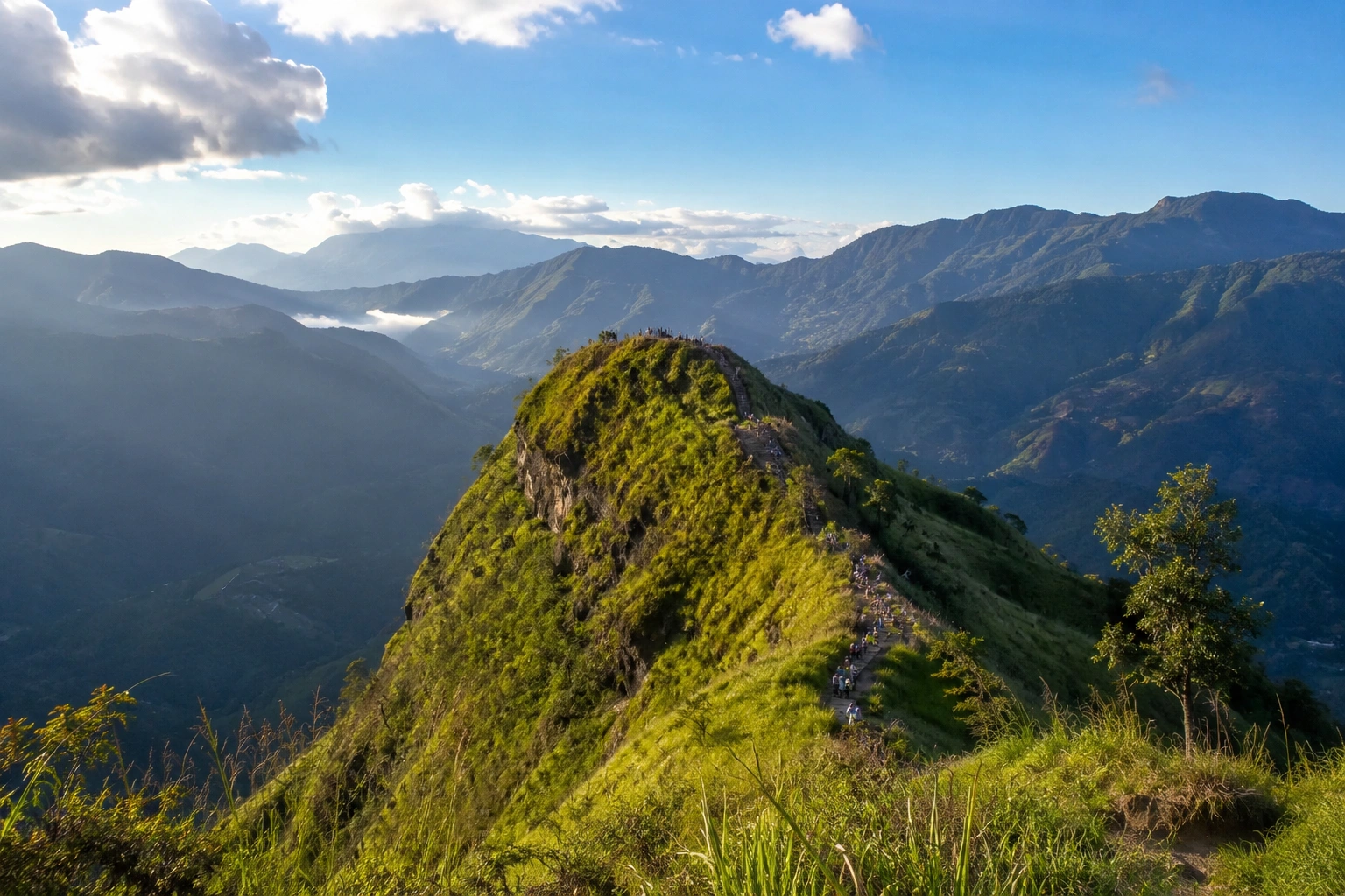 Visitors enjoying the panoramic views from Little Adam's Peak in Ella, Sri Lanka, overlooking lush tea plantations, rolling hills, and scenic mountain landscapes.